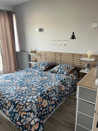 a bedroom with a bed with a blue comforter at Appart Cosy Centre ville -proche gare in Châtellerault