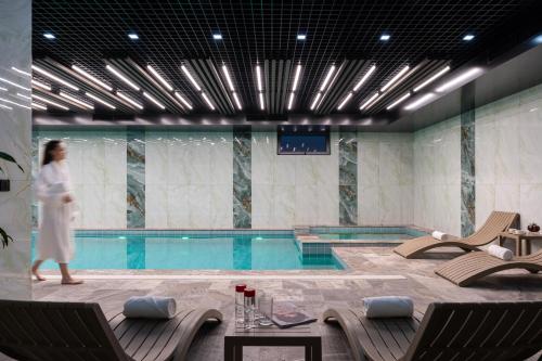 a woman is walking by a swimming pool at Grand Dior in Tashkent