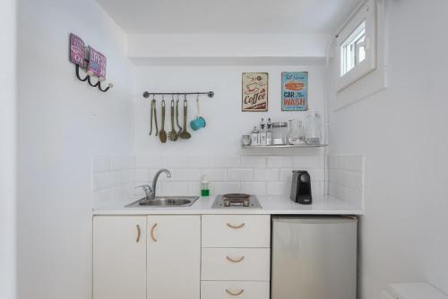 a kitchen with white cabinets and a sink at Kastella Sunset Villa Three in Kithnos