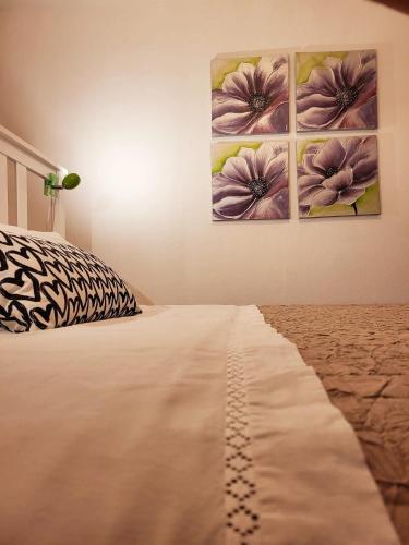 a bedroom with three paintings on the wall at LA TERRAZZA appartamento di vacanza in Collina d'Oro