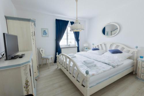 a bedroom with a white bed and a television at Landhaus Süchterscheid in Süchterscheid