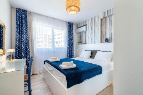 a white bedroom with blue curtains and a bed at Blue Eye Apartment in Sarandë
