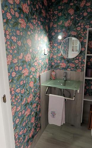 a bathroom with floral wallpaper with a sink and a mirror at Les Casetes in La Senia