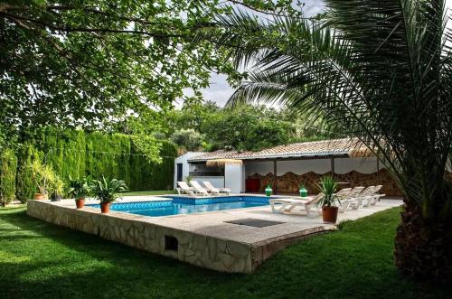 a swimming pool with chairs and a house at Alojamiento turístico Loma Alta in Cambil