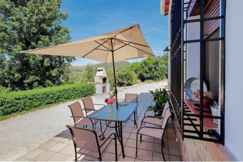 a patio with a table and chairs and an umbrella at Alojamiento turístico Loma Alta in Cambil