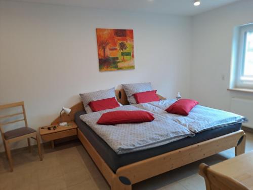 a bedroom with a bed with red pillows on it at Ferienhaus Ottilie in Gladenbach