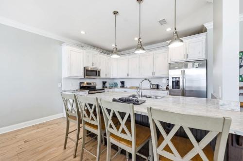 a kitchen with white cabinets and a large island with bar stools at Anchor Down Luxury Ocean View Beach House w Pool in Myrtle Beach