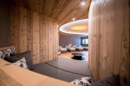 a room with wooden walls and a room with couches at Hotel Waldheim in Valle Di Casies