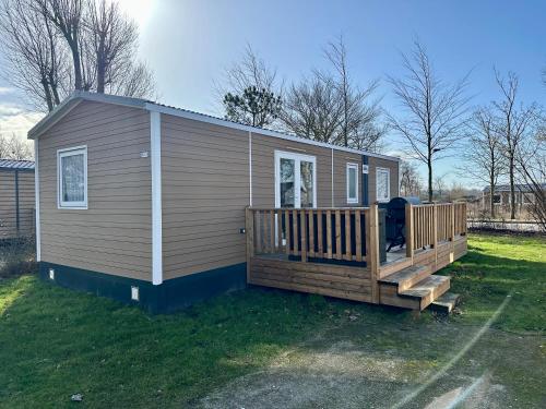 a small house with a large deck on the grass at Chalet Levy in Lauwersoog