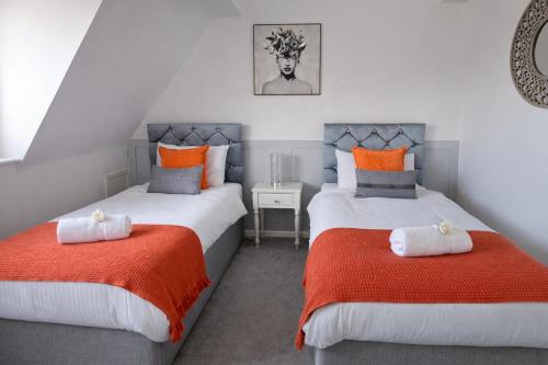 a bedroom with two beds with orange and white pillows at That's Amore House 3 bedroom house with parking walking distance to Sandbach town in Sandbach