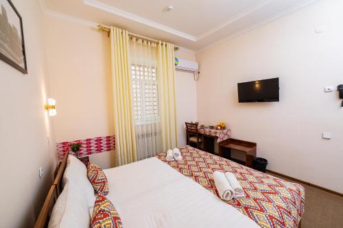 a bedroom with a bed and a tv on the wall at Caravan Boutique Ichan Kala in Khiva