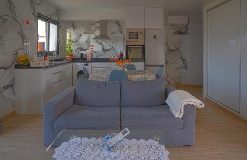 a living room with a blue couch and a kitchen at Moonfall House in Arco da Calheta