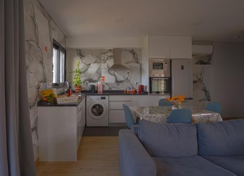 a kitchen and living room with a blue couch and a table at Moonfall House in Arco da Calheta