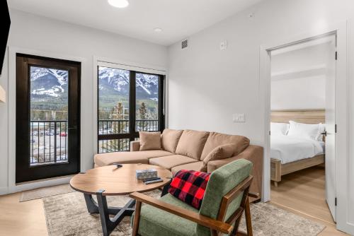 a living room with a couch and a table and a bed at Modern mountain luxury with stunning views in Canmore