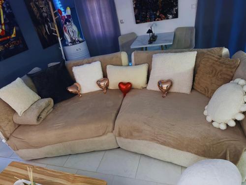 a brown couch with pillows and a red heart on it at Maison cocooning , avec double jacuzzi et piscine in La Machine