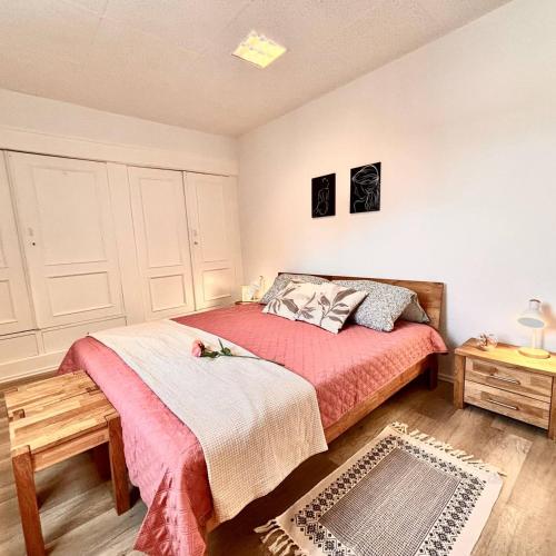 a bedroom with a bed with a red bedspread and a table at Ferienwohnung Meerane Zentrum in Meerane
