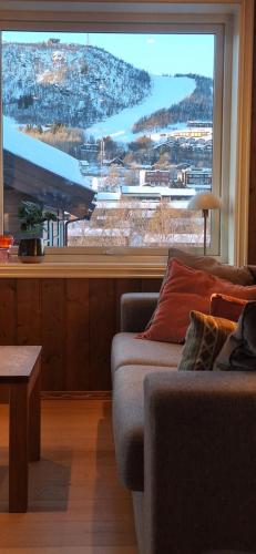 a living room with a couch and a large window at Sentral leilighet på Geilo in Geilo