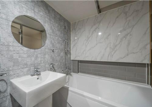 a bathroom with a sink and a tub and a mirror at 9AVENUE hotel in Daegu