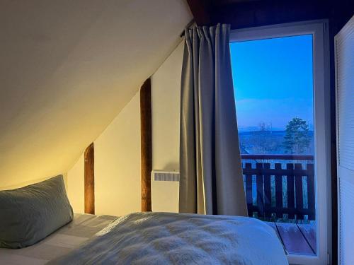 a bedroom with a bed and a large window at Ferienhaus Lisa am Silbersee in Frielendorf