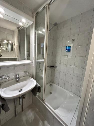 a white bathroom with a sink and a shower at Adelhome Studio mit Gartensitzplatz in Adelboden