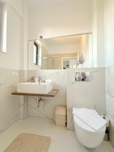 a white bathroom with a sink and a toilet at Amira Residence in Eforie Nord