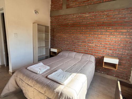 a bedroom with a brick wall and a bed at Laguna de los Cisnes in Perito Moreno