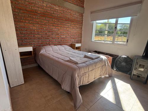 a bedroom with a bed and a brick wall at Laguna de los Cisnes in Perito Moreno