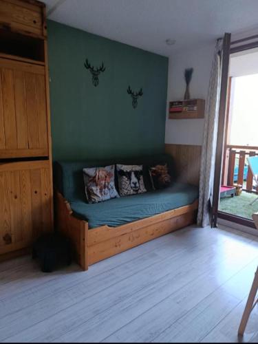 a bed in a room with a green wall at Studio en station de ski familiale, vue sur les montagnes in La Morte
