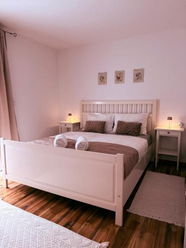 a white bed in a bedroom with two night stands at Apartments Pablo Novalja in Novalja