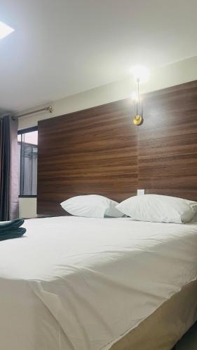 a bedroom with a large white bed with a wooden headboard at Hotel MM AEROPORTO BRASÍLIA in Núcleo Bandeirante
