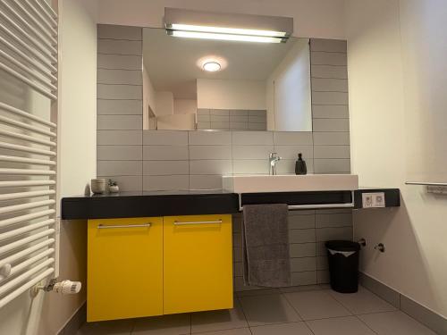 a bathroom with a yellow sink and a mirror at Apartma S in Sežana