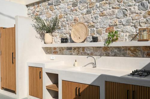 a kitchen with a sink and a stone wall at Villa Pothaia in Myrties