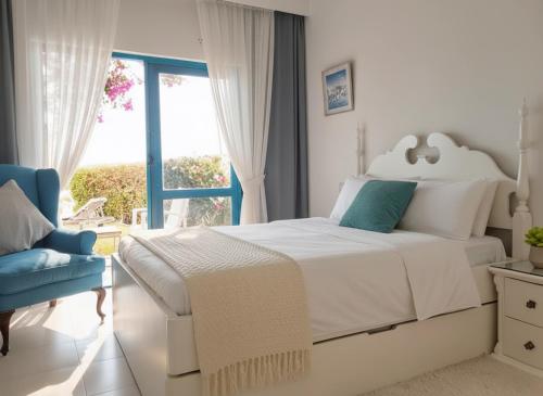 a white bedroom with a bed and a blue chair at Unique cozy villa sea view in Hurghada