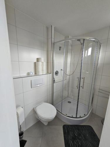 a white bathroom with a shower and a toilet at Ferienhaus Meeresbrise in Wurster Nordseeküste