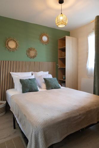 a bedroom with a large bed with green walls at Le reflet de Cabourg avec accès direct plage in Cabourg