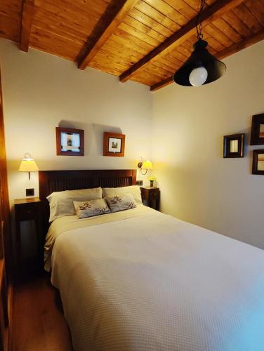 a bedroom with a large white bed with a wooden ceiling at Cau La Mar in Lastres