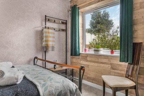 a bedroom with a bed and a window and a chair at 2BR Apartment Free Parking Sleeps 4 Cheltenham in Cheltenham