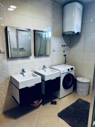 a bathroom with two sinks and a washing machine at SF Apartments Lux in Dobra Voda