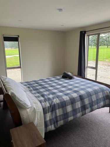ein Schlafzimmer mit einem Bett und einer blau-karierten Decke in der Unterkunft Shinness in Ashwick Flat