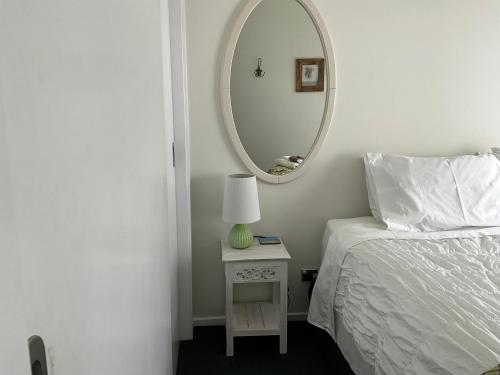 a bedroom with a bed and a round mirror at Jennie's In Whitianga in Whitianga
