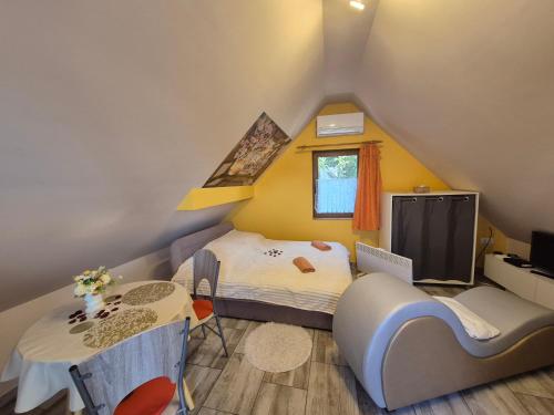 a small attic bedroom with a bed and a table at Flóra apartmanház a Balatonnál in Lovas