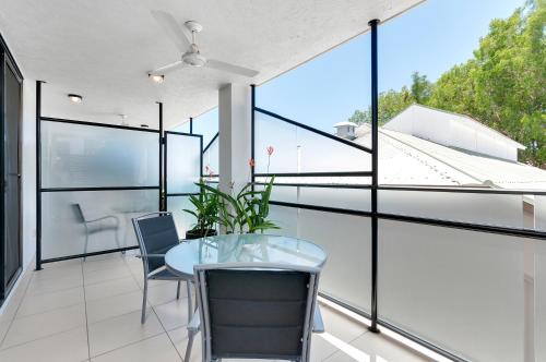 a room with a table and chairs on a balcony at Elysium Apartments in Palm Cove