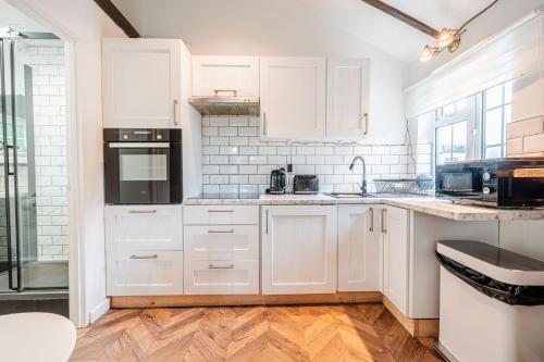 a kitchen with white cabinets and black appliances at New Forest Cottage with Hot Tub, Fireplace and Private Garden in Cadnam