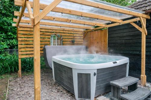 a hot tub in a backyard with a pergola at New Forest Cottage with Hot Tub, Fireplace and Private Garden in Cadnam