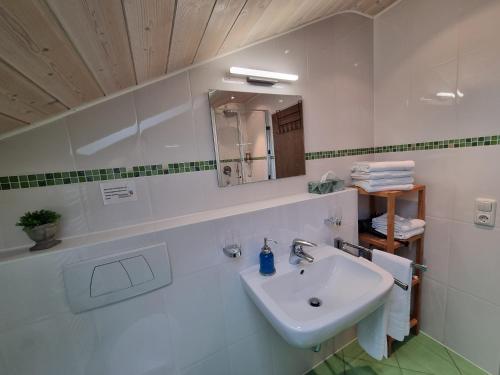 a white bathroom with a sink and a mirror at Zugspitze 6 mit SAUNA in Farchant bei Garmisch-Partenkirchen in Farchant