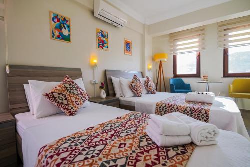 a hotel room with two beds and a chair at Ada Olympos Otel in Bozcaada