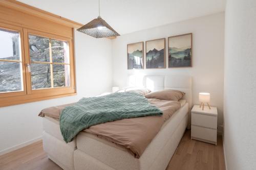a bedroom with a bed with a green blanket on it at Alpenblick in Beatenberg