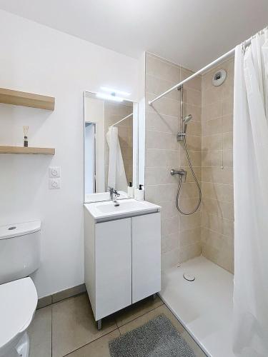 a white bathroom with a shower and a sink at Appartement cosy à Bron in Bron