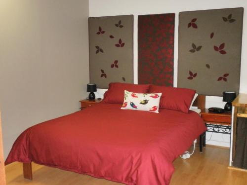 a bedroom with a red bed with a red comforter at The Cosy Cottage in Port Sorell