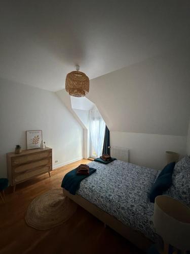 a bedroom with a bed with a blue comforter and a window at Appartement Maisonnette pour 4 personnes in La Ferté-Vidame